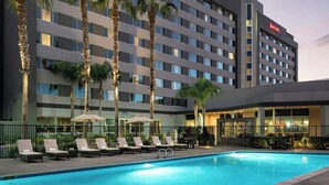 A Marriott hotel with a swimming pool, sun loungers, palm trees, and outdoor seating. - Bakersfield Marriott at the Convention Center (Bakersfield)