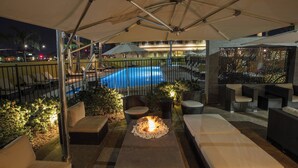 An outdoor patio area with a pool, lounge seating, and a fire feature. - Bakersfield Marriott at the Convention Center (Bakersfield)