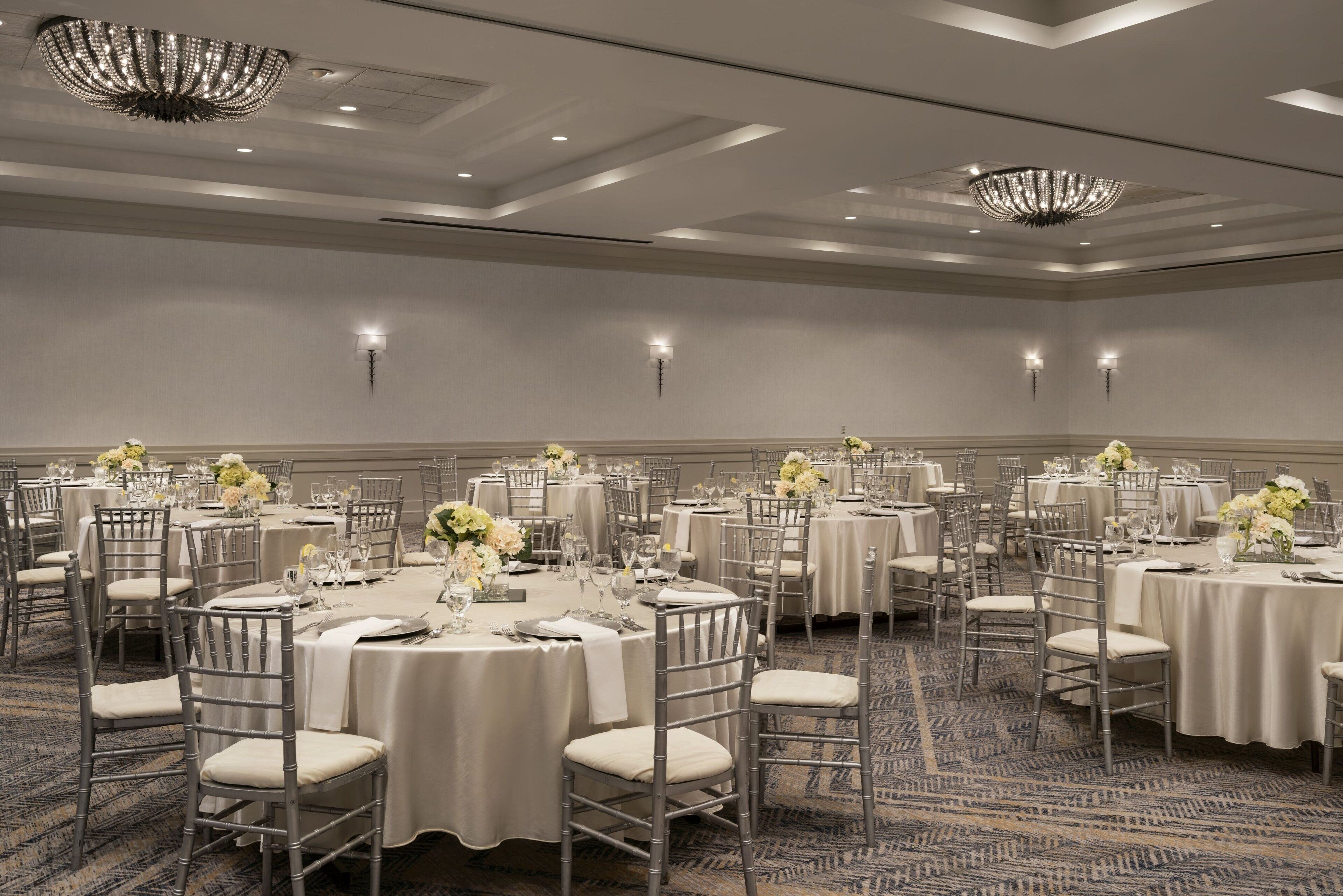 Un salón de banquetes con mesas redondas, sillas y candelabros.