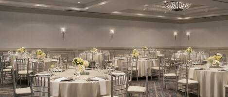 Un salón de banquetes con mesas redondas, sillas y candelabros.
