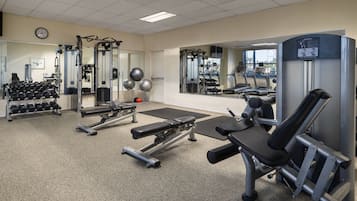 Un gimnasio con varios equipos de ejercicio, incluyendo mancuernas, una prensa de banca y una máquina de extensión de piernas.