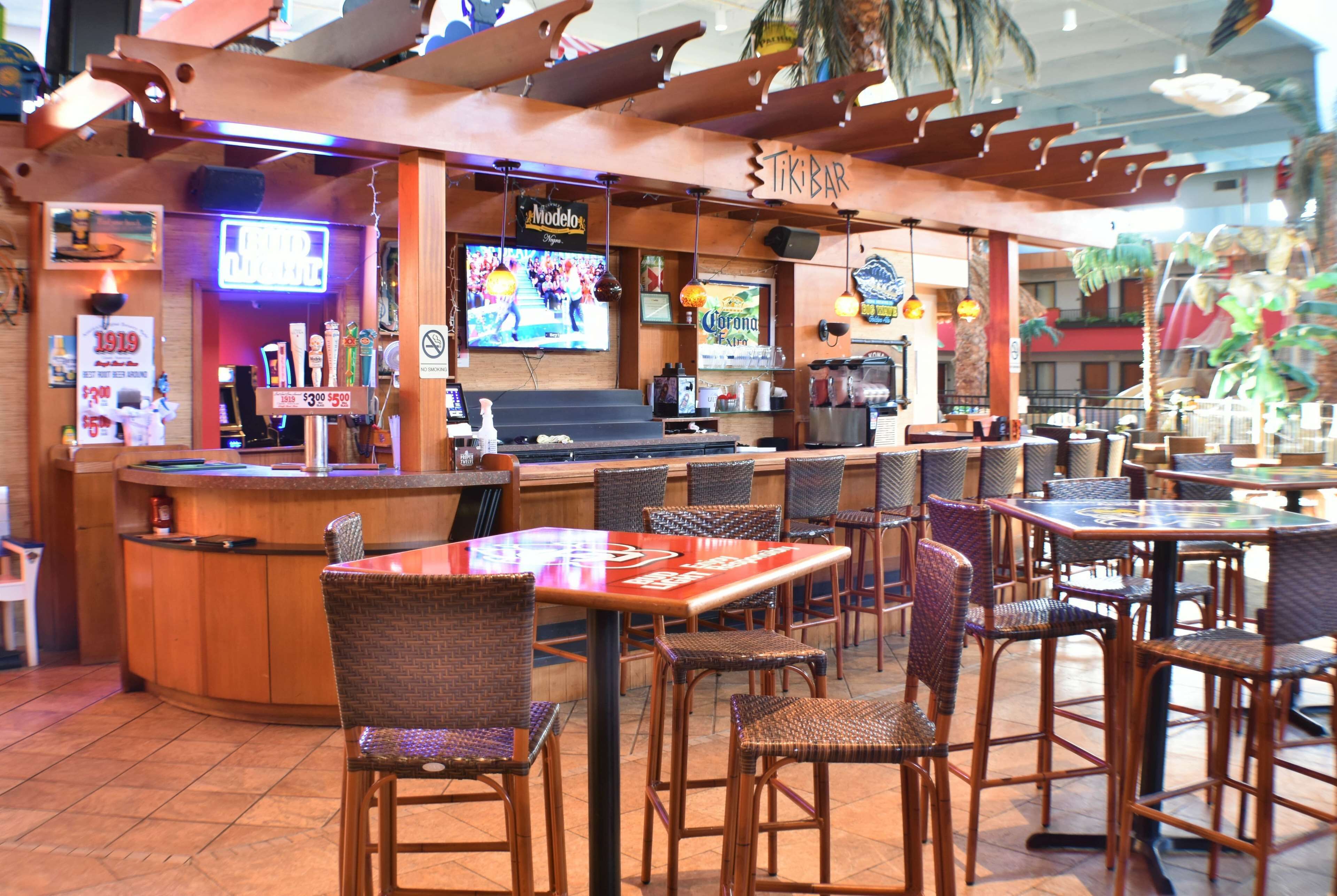 A tiki bar with a bar counter, wicker chairs, and tables.