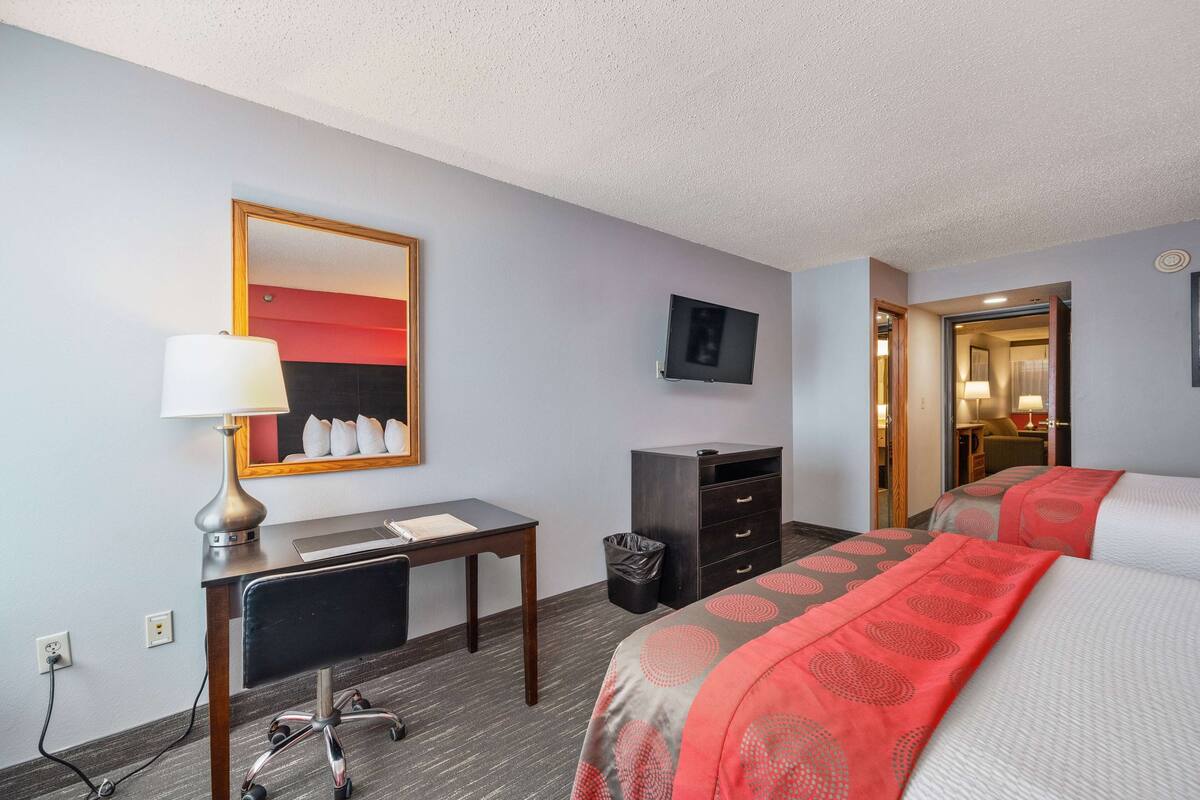A hotel room with a desk, chair, bed, and a television on the wall.
