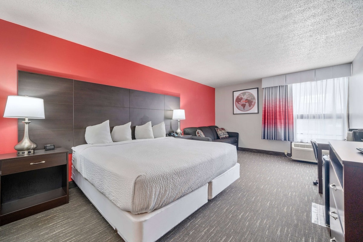 A hotel room with a large bed, bedside lamps, a desk, and a chair.