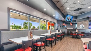 Un restaurant avec des banquettes et des tables, un écran de télévision et une vue sur l’extérieur.