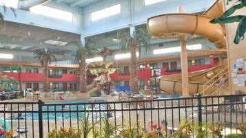 Un área de piscina interior con tobogán de agua, palmeras y una decoración con forma de barco.