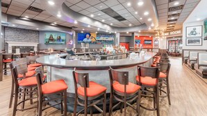 Un restaurant moderne avec un bar central, des chaises rembourrées de couleur rouge et une enseigne indiquant « SALLE D’ÉQUIPE ».