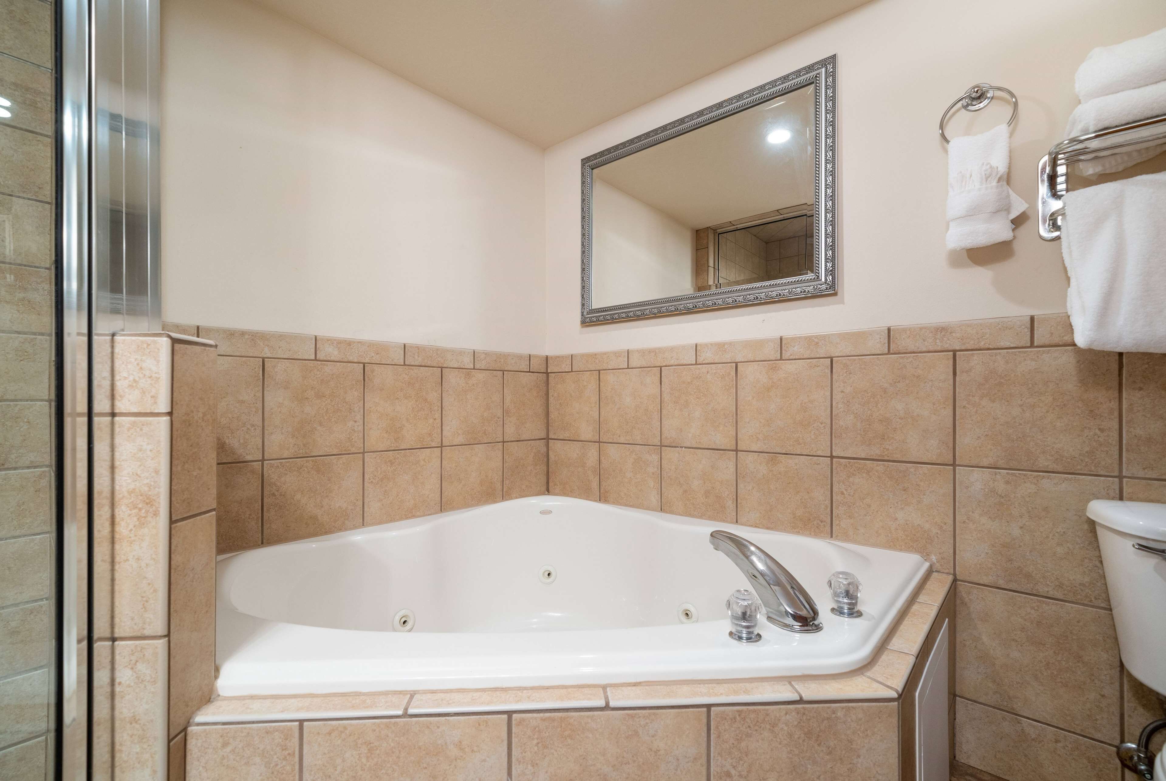 A bathroom with a freestanding bathtub, a wall-mounted mirror, and a towel rack with towels.