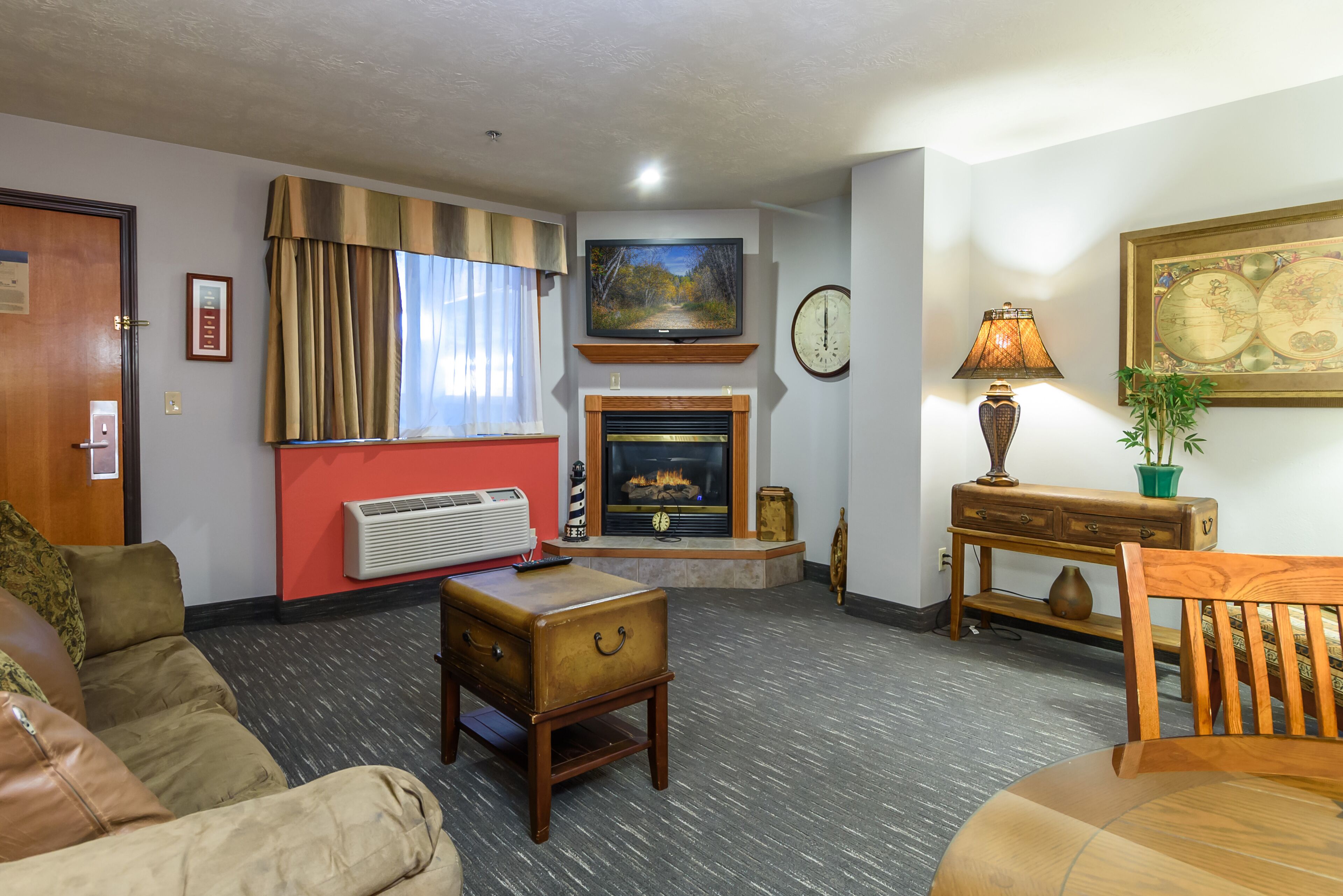 A living room with a fireplace, a television, a clock, and a globe on the wall.