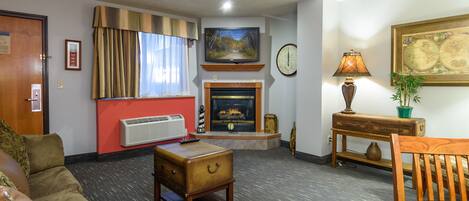 A living room with a fireplace, a television, a clock, and a globe on the wall.