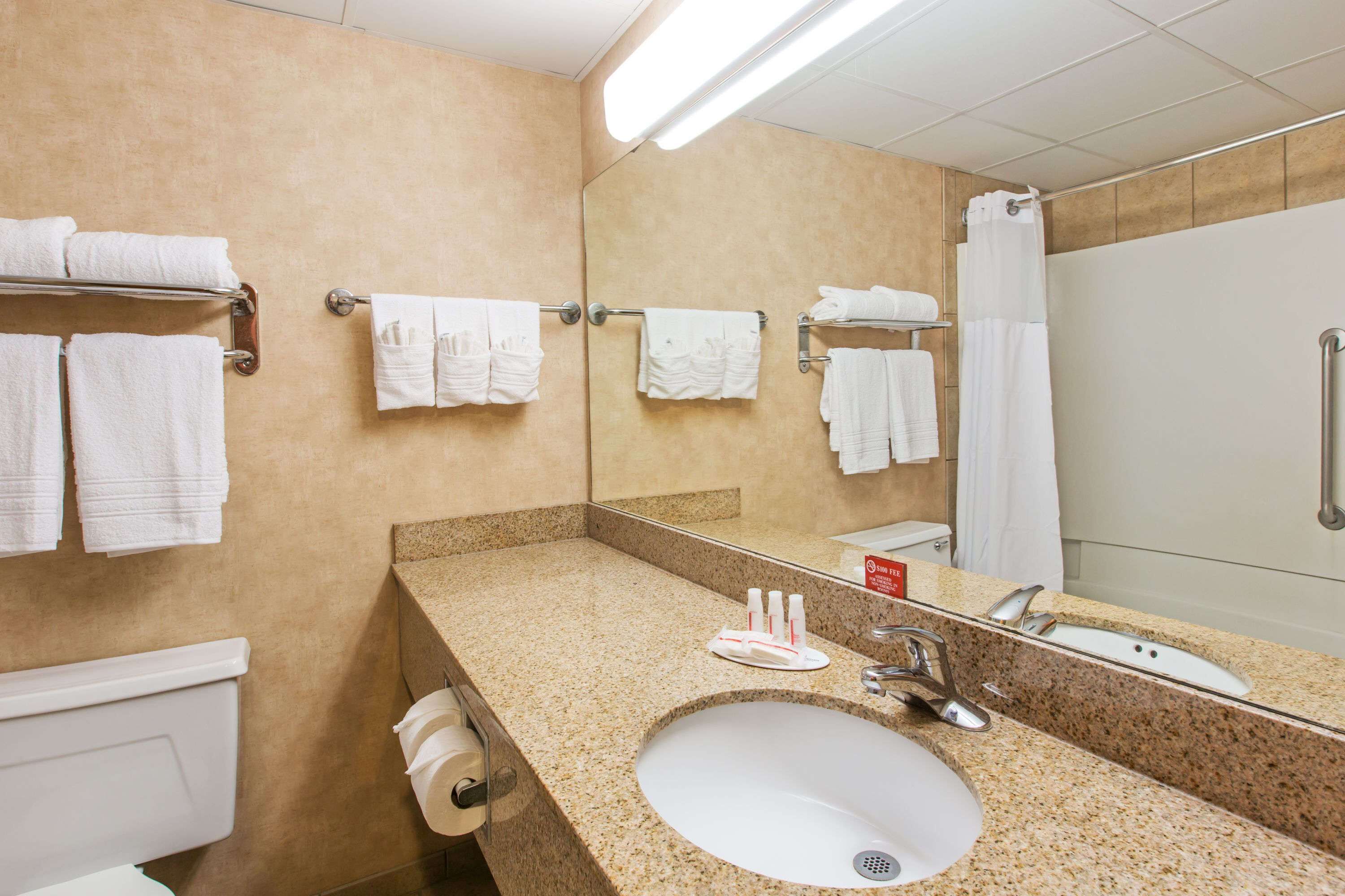 A bathroom with a sink, mirror, towel rack, and shower.
