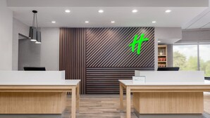 Een moderne receptie met twee balies, een wand van verticaal hout en een groen logo.