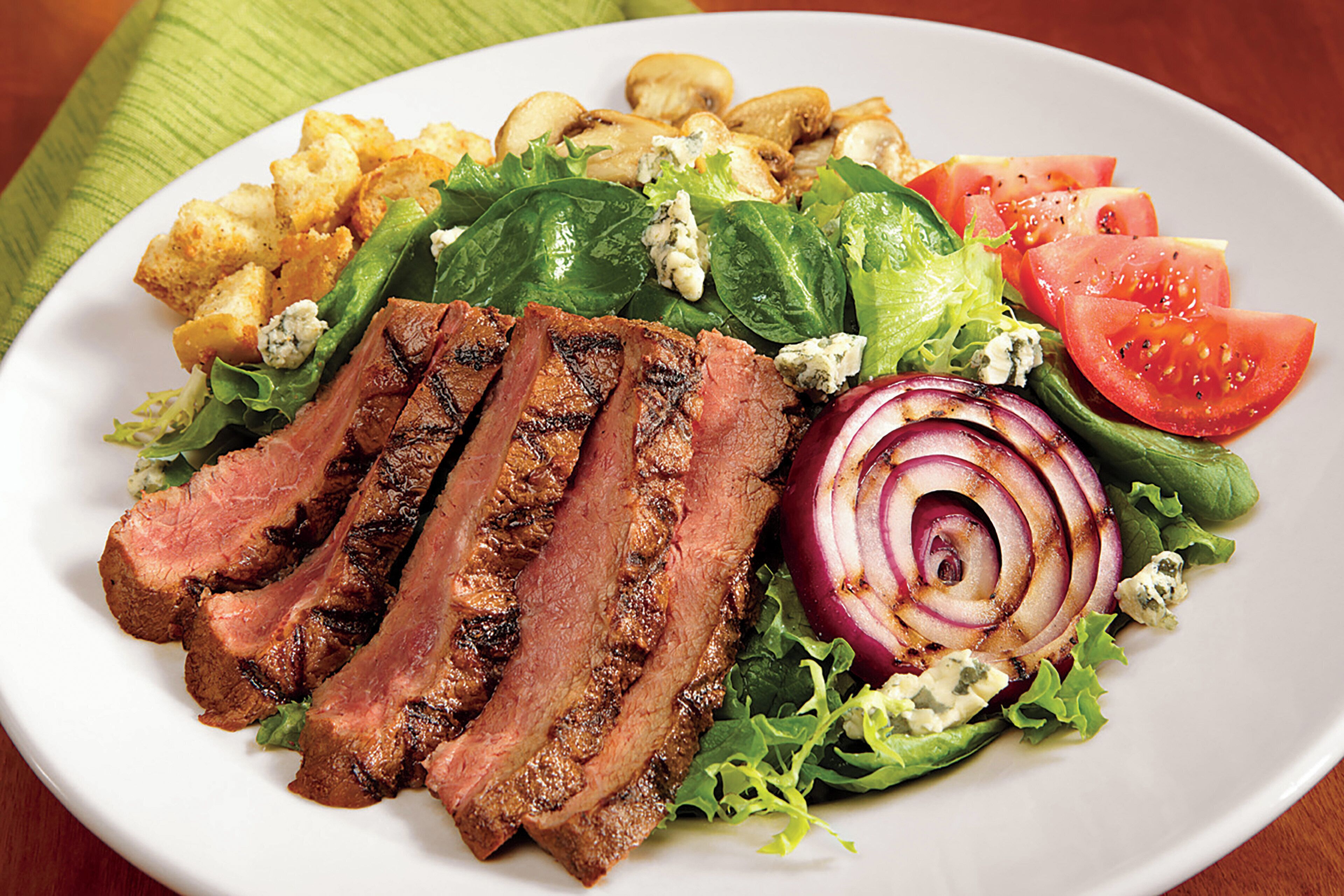 Une assiette de nourriture comprenant de la viande grillée, des légumes et des croûtons en accompagnement.