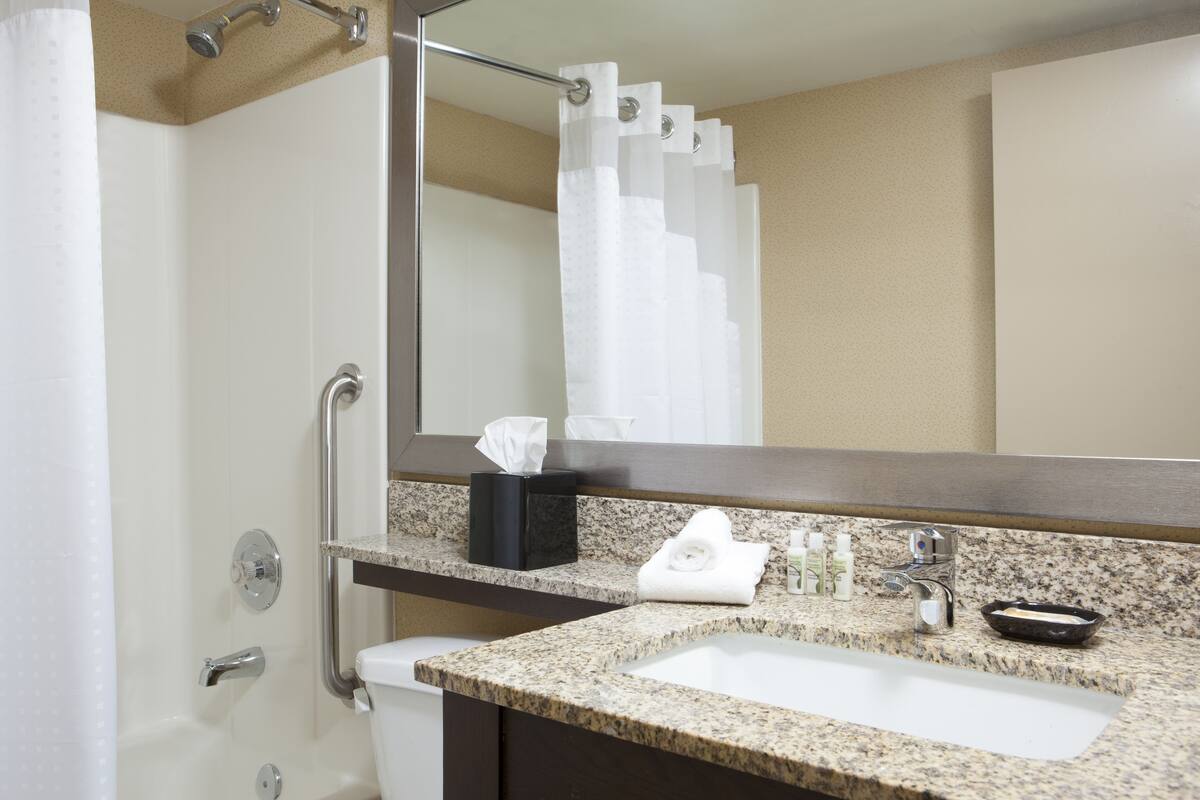 Une salle de bain équipée d’un lavabo, d’un miroir, d’une serviette et d’articles de toilette.