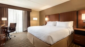 A hotel room with a large bed, a desk, a chair, and a lamp. - Holiday Inn Hotel & Suites Des Moines - Northwest by IHG (Urbandale)