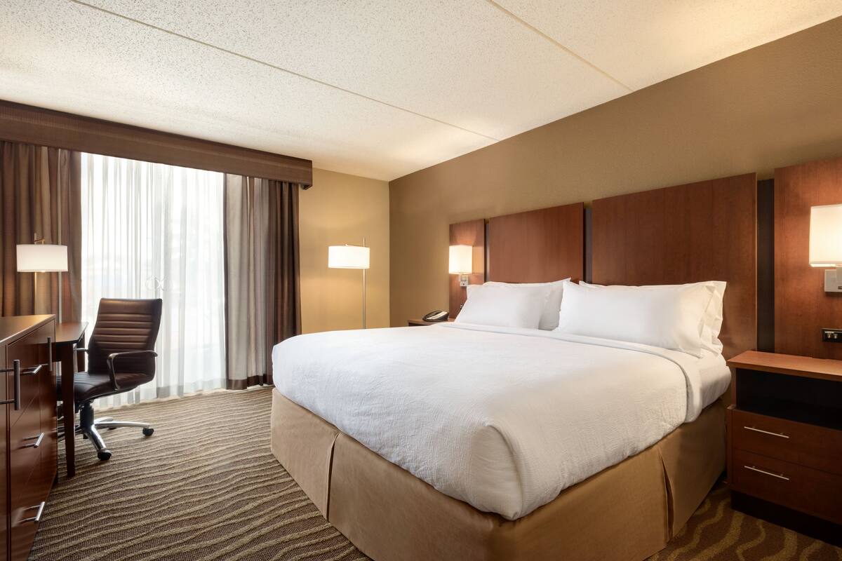 Une chambre d’hôtel avec un grand lit, un bureau, une chaise et une lampe.
