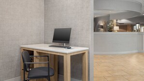 Een moderne kantoorruimte met een houten bureau, een zwarte bureaustoel en een computer.