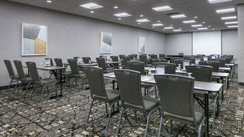Una sala conferenze con diversi tavoli e sedie, dotata di bottigliette d'acqua e cartellini con i nomi.