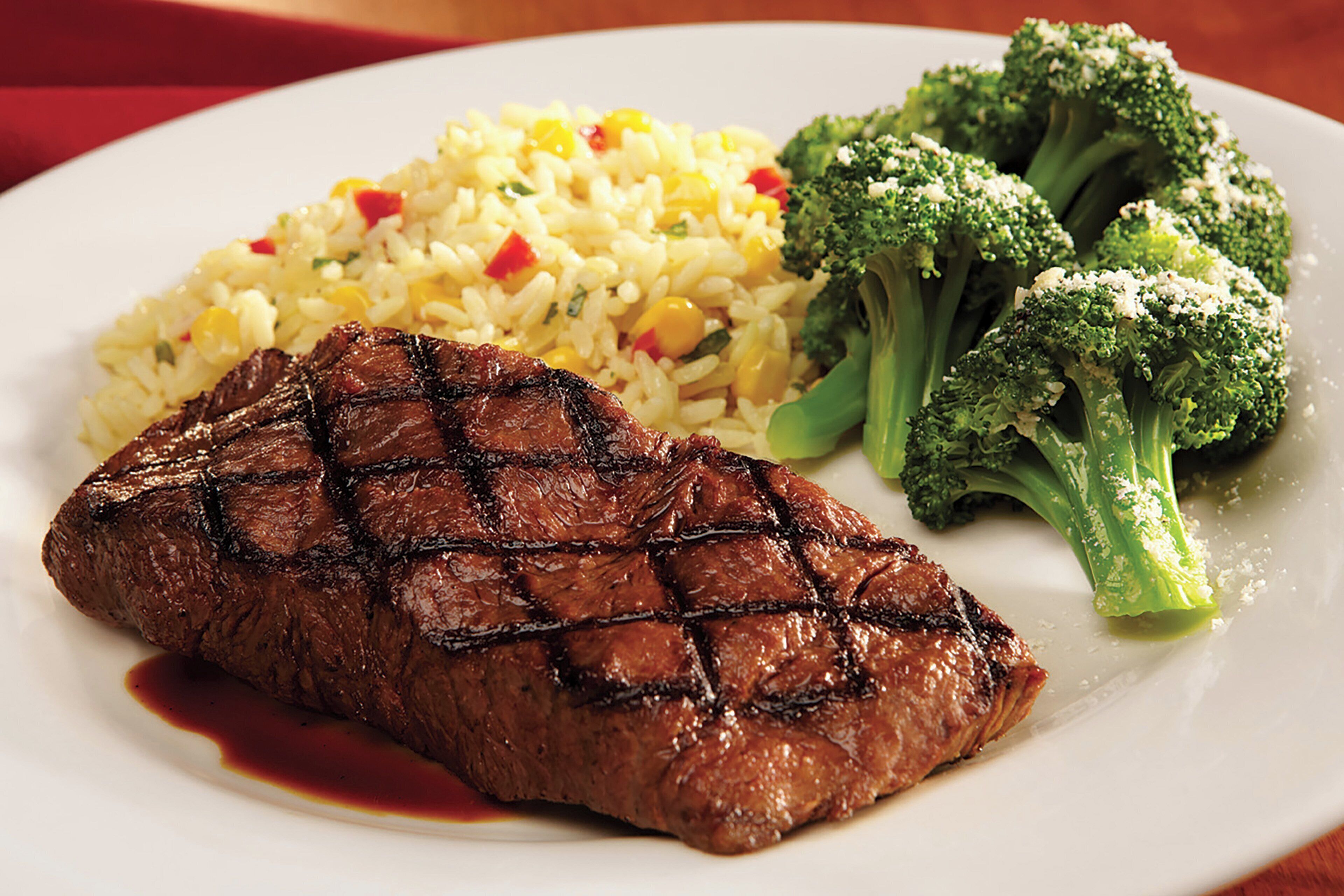A plate with a grilled steak, rice, and broccoli.