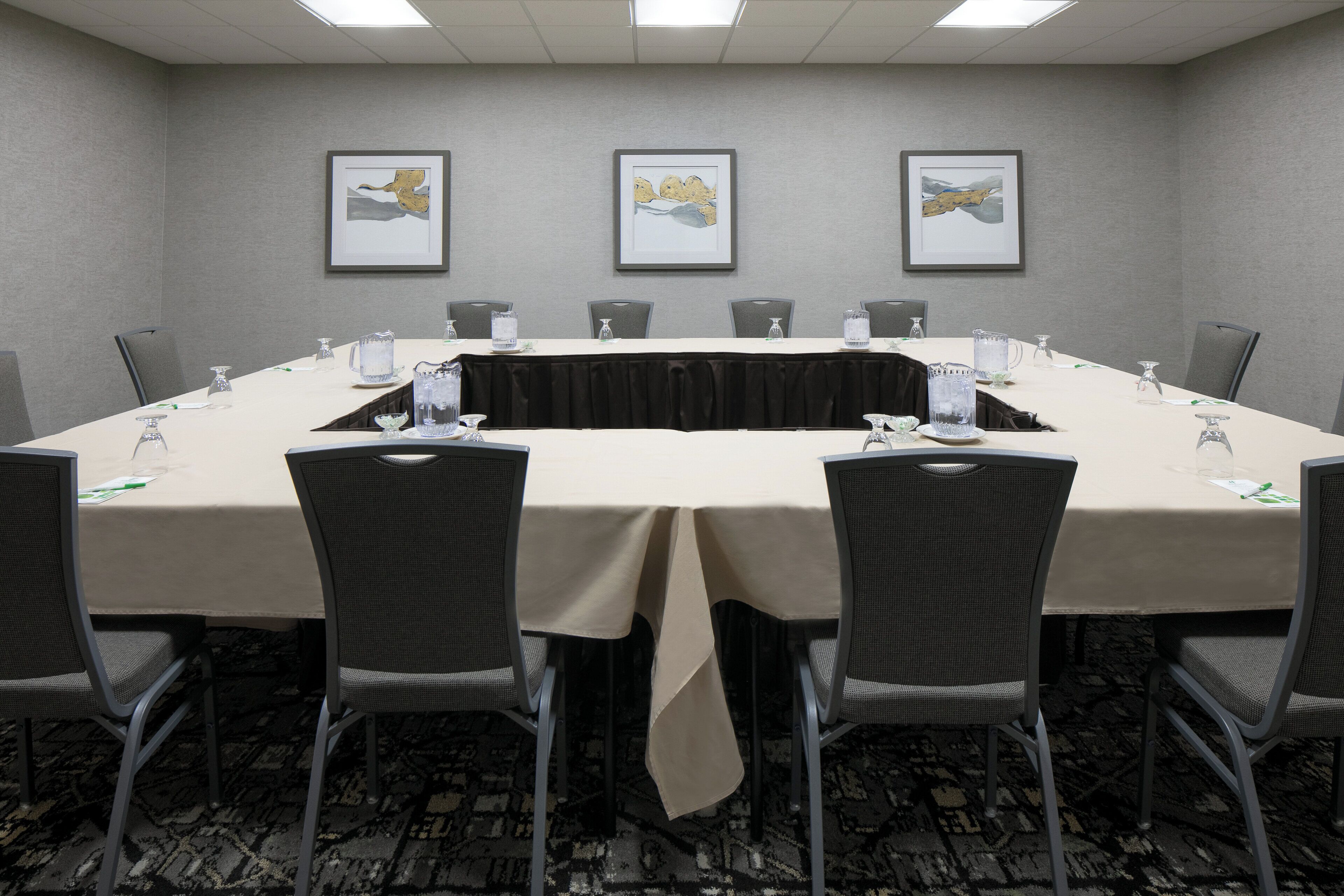 A conference room with a long table, chairs, and framed artwork on the walls.