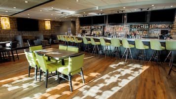 A bar area with a long counter, multiple stools, and a seating area with tables and chairs.
