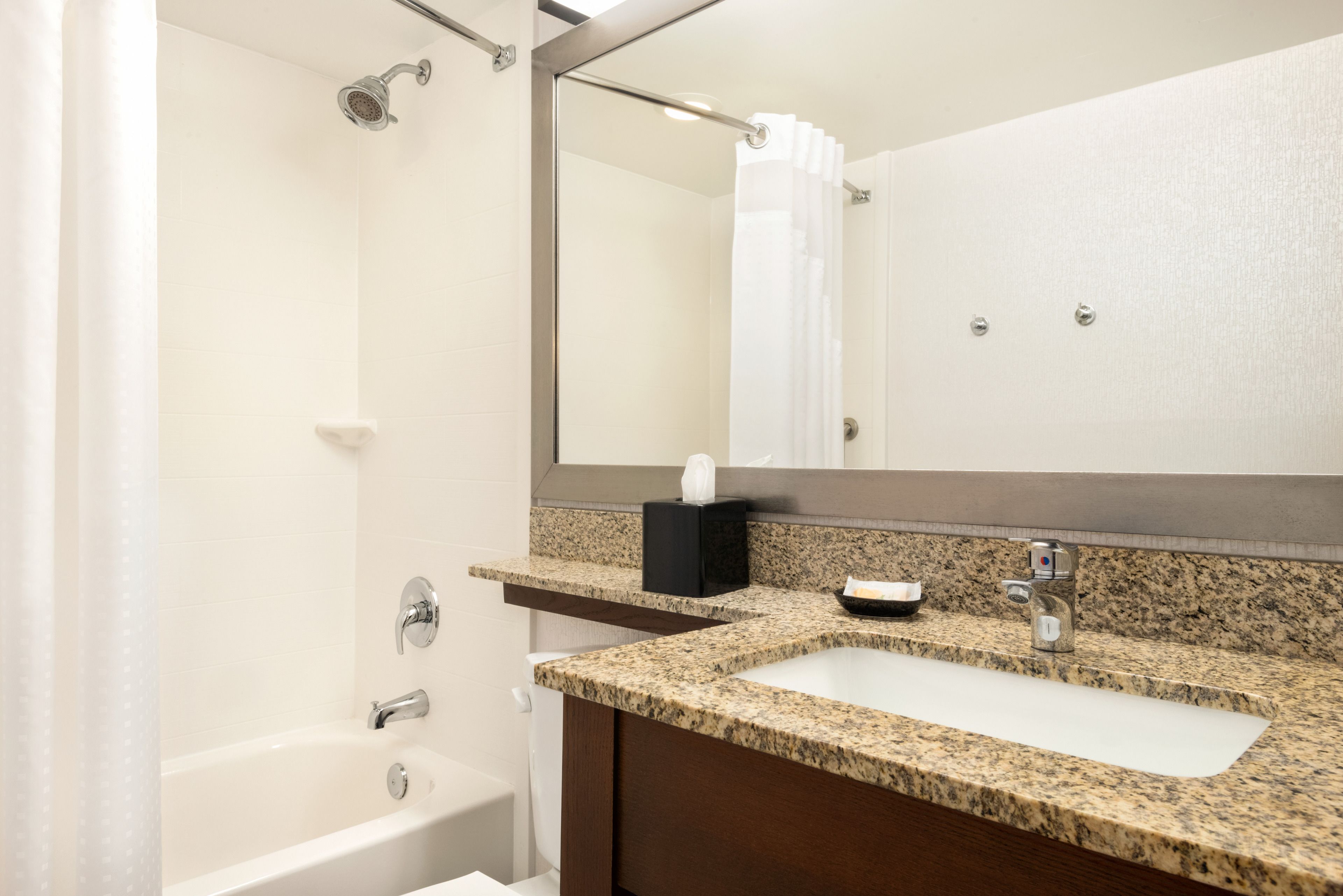 A bathroom with a sink, mirror, and shower.