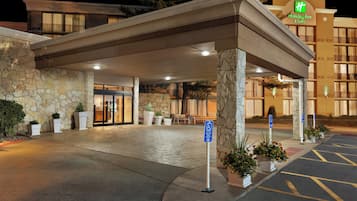 A hotel entrance with a covered walkway, stone facade, and handicap parking sign.
