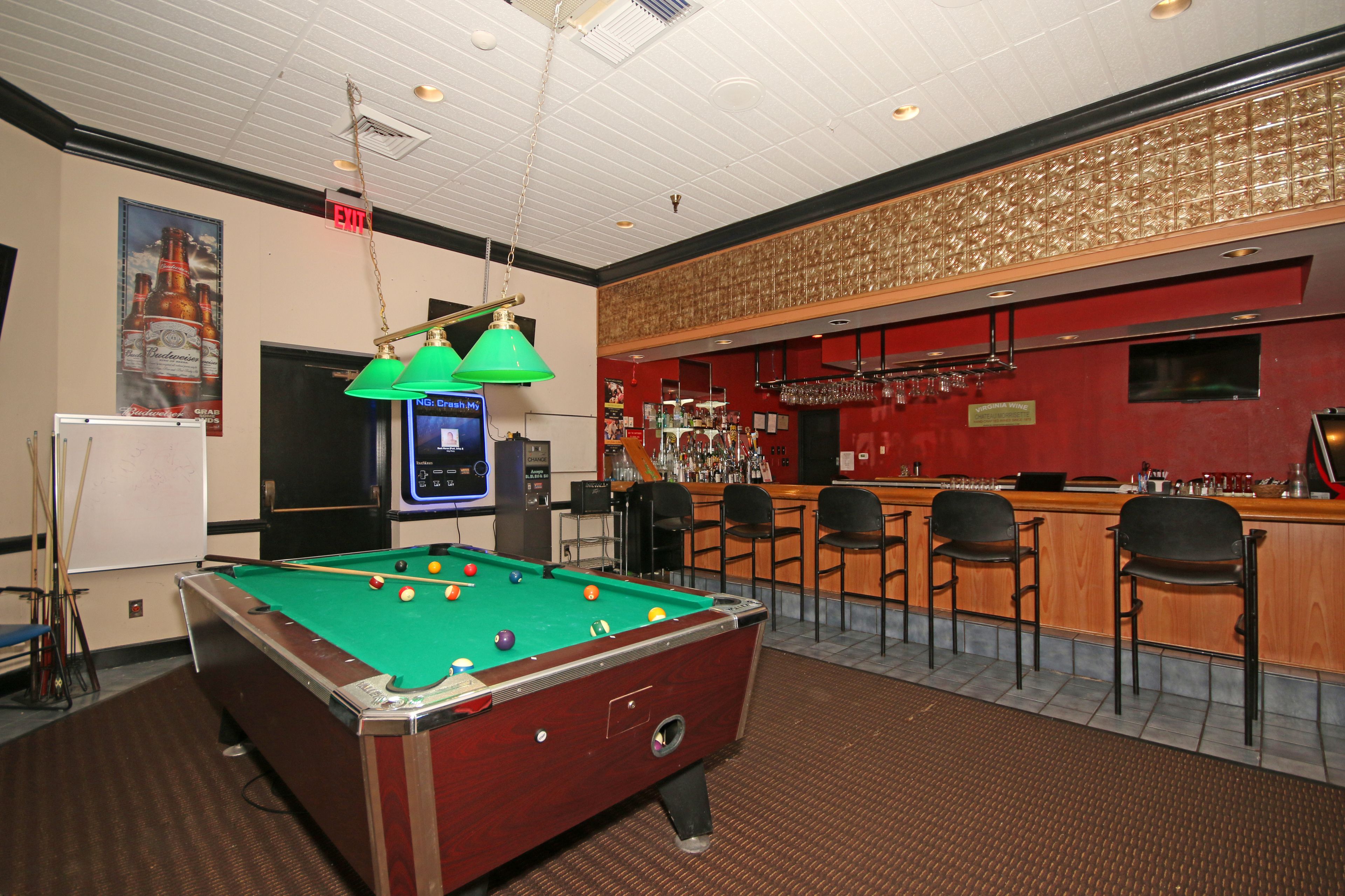 A pool table with a bar area in the background.
