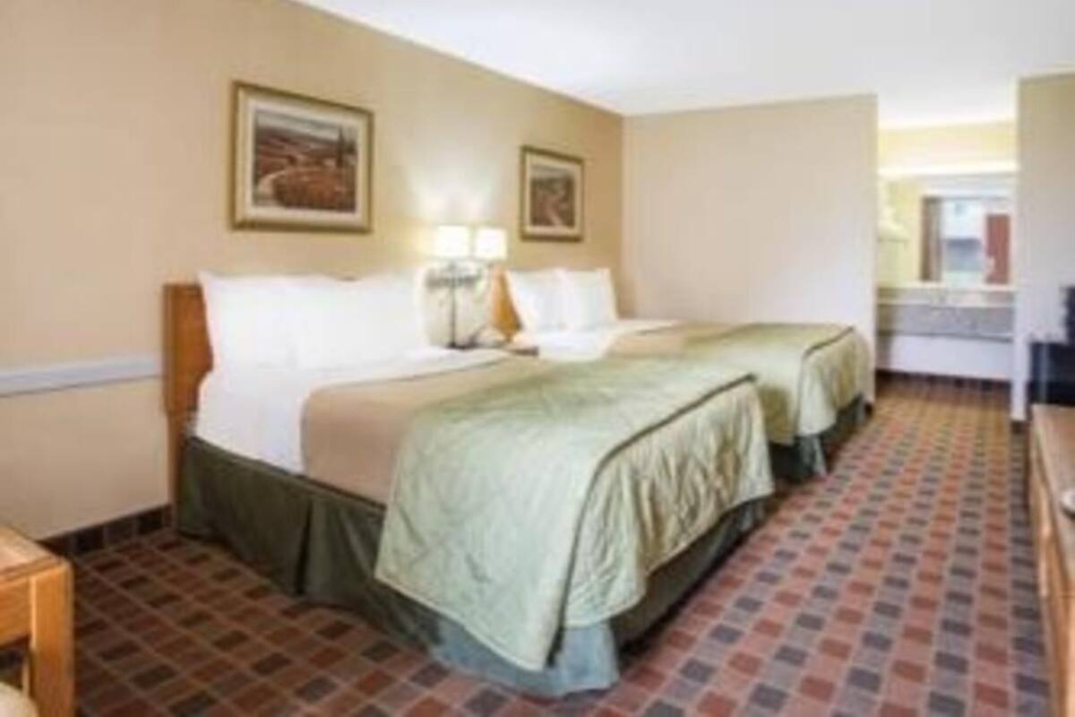 Une chambre d’hôtel avec deux lits, un bureau et une fenêtre.