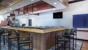 Uma cozinha moderna com uma ilha central, banquetas de bar e piso ladrilhado.