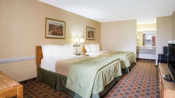 A hotel room with two beds, a desk, a TV, and a bathroom visible through an open door.