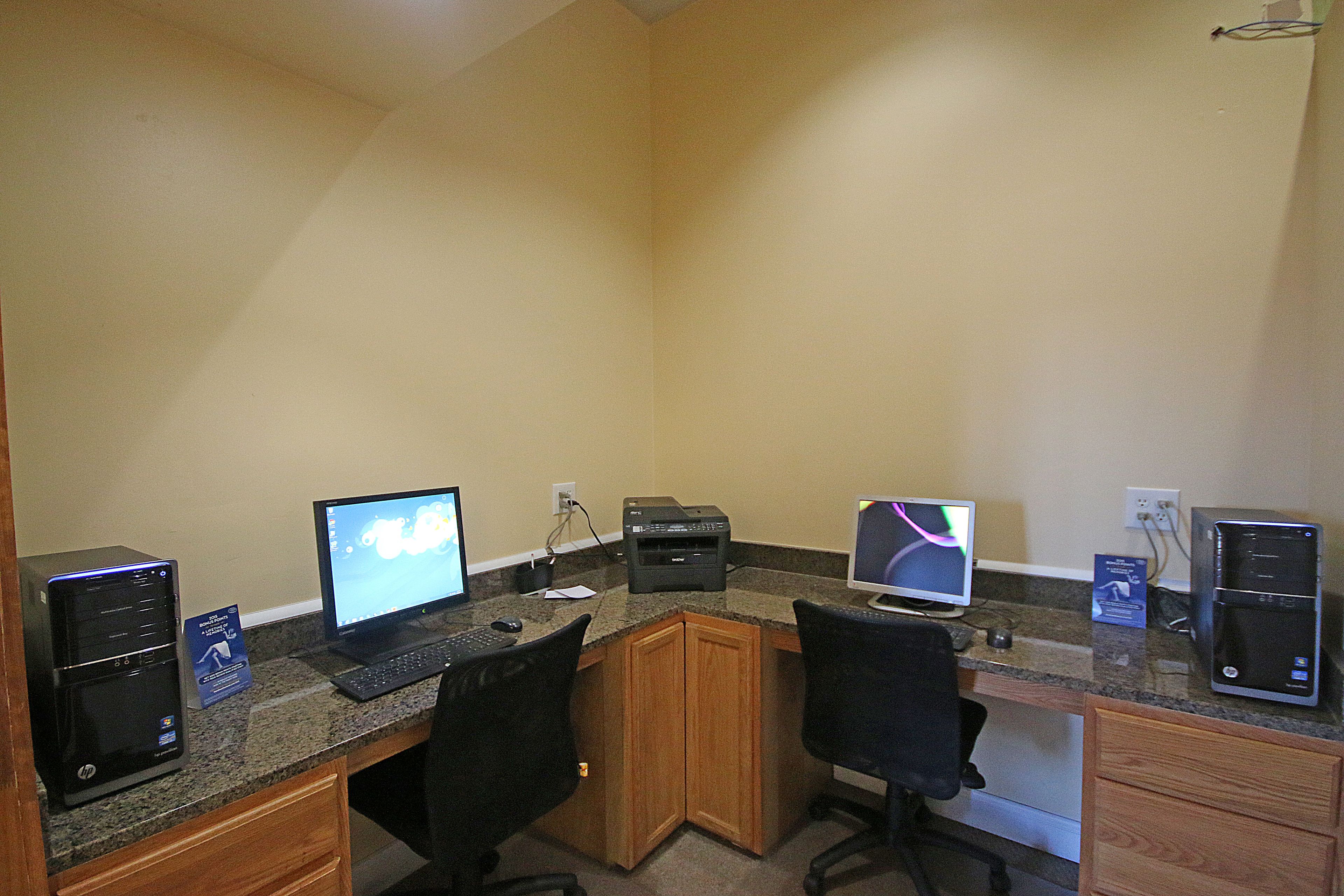 Un espacio de trabajo con dos escritorios, cada uno con una computadora, una impresora y una silla.