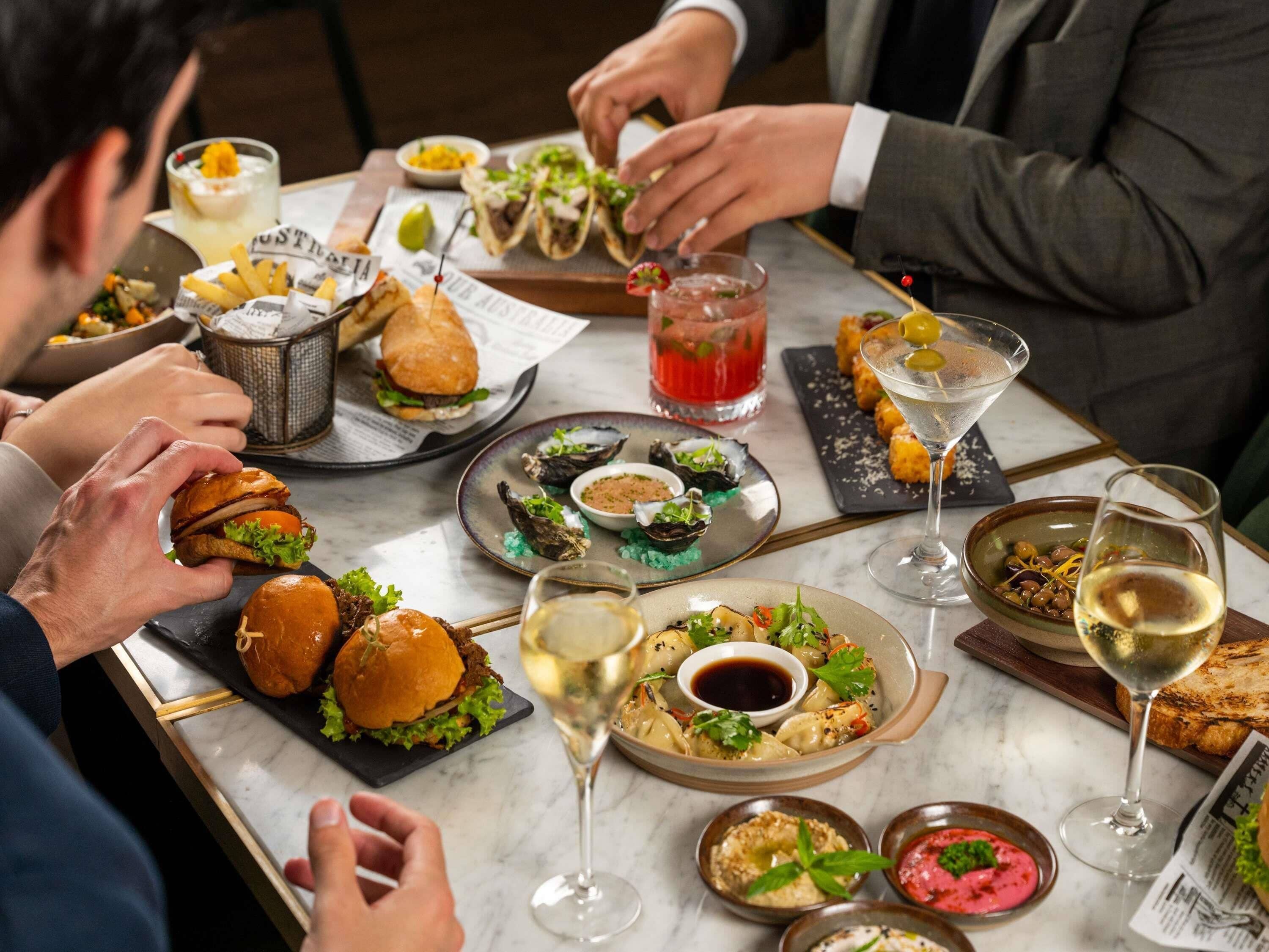 A dining table with various dishes, drinks, and a newspaper.