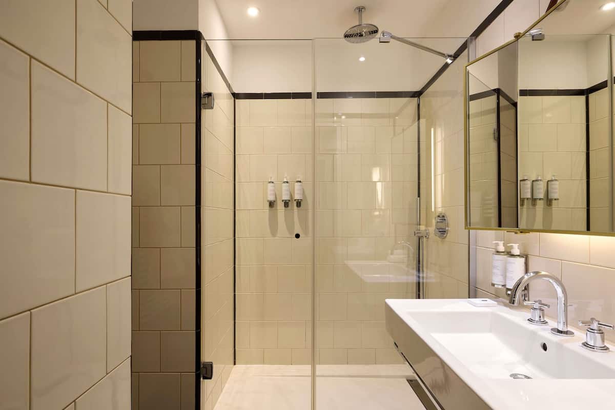 A modern bathroom with a glass-enclosed shower, a large mirror, and a dual sink vanity.