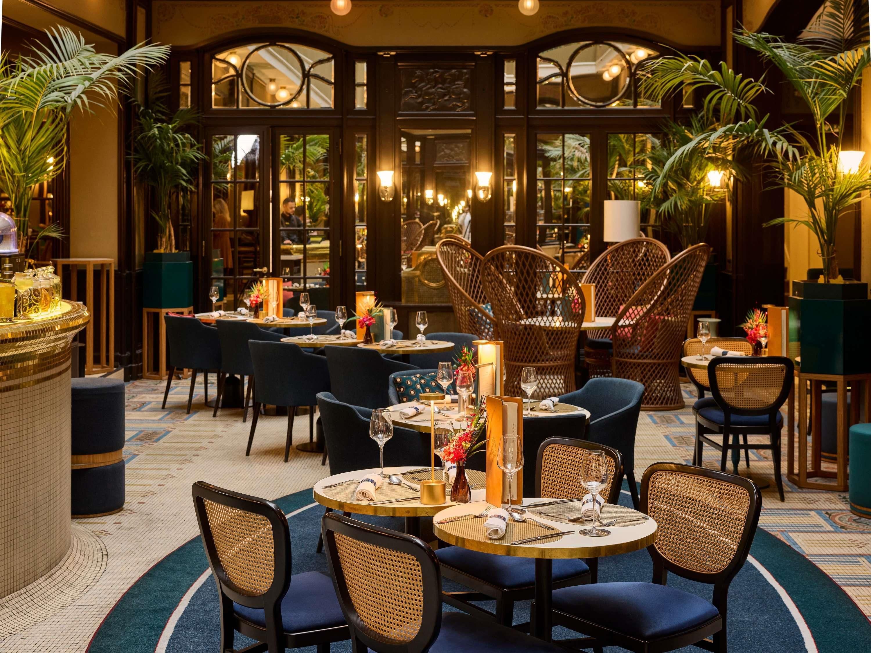 Een restaurant met ronde tafels, rieten stoelen en een bar.
