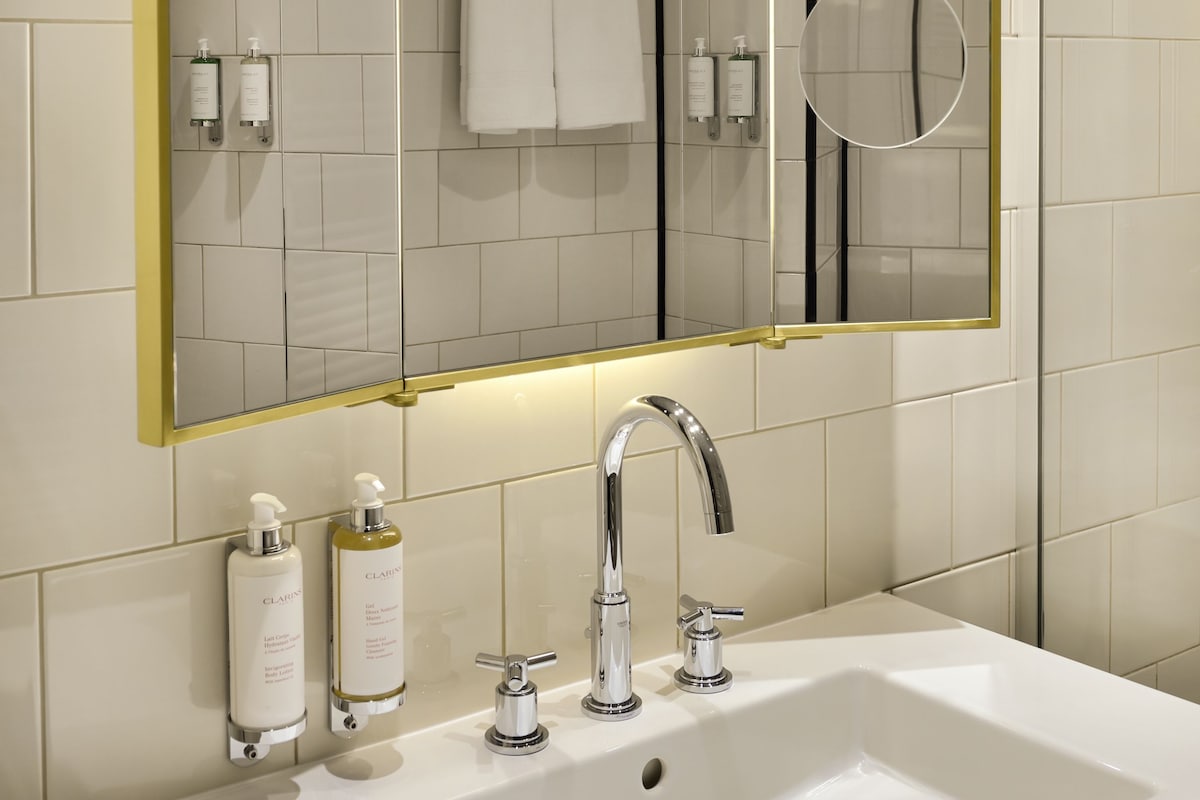 A bathroom with a large mirror, a sink, and two bottles of toiletries.