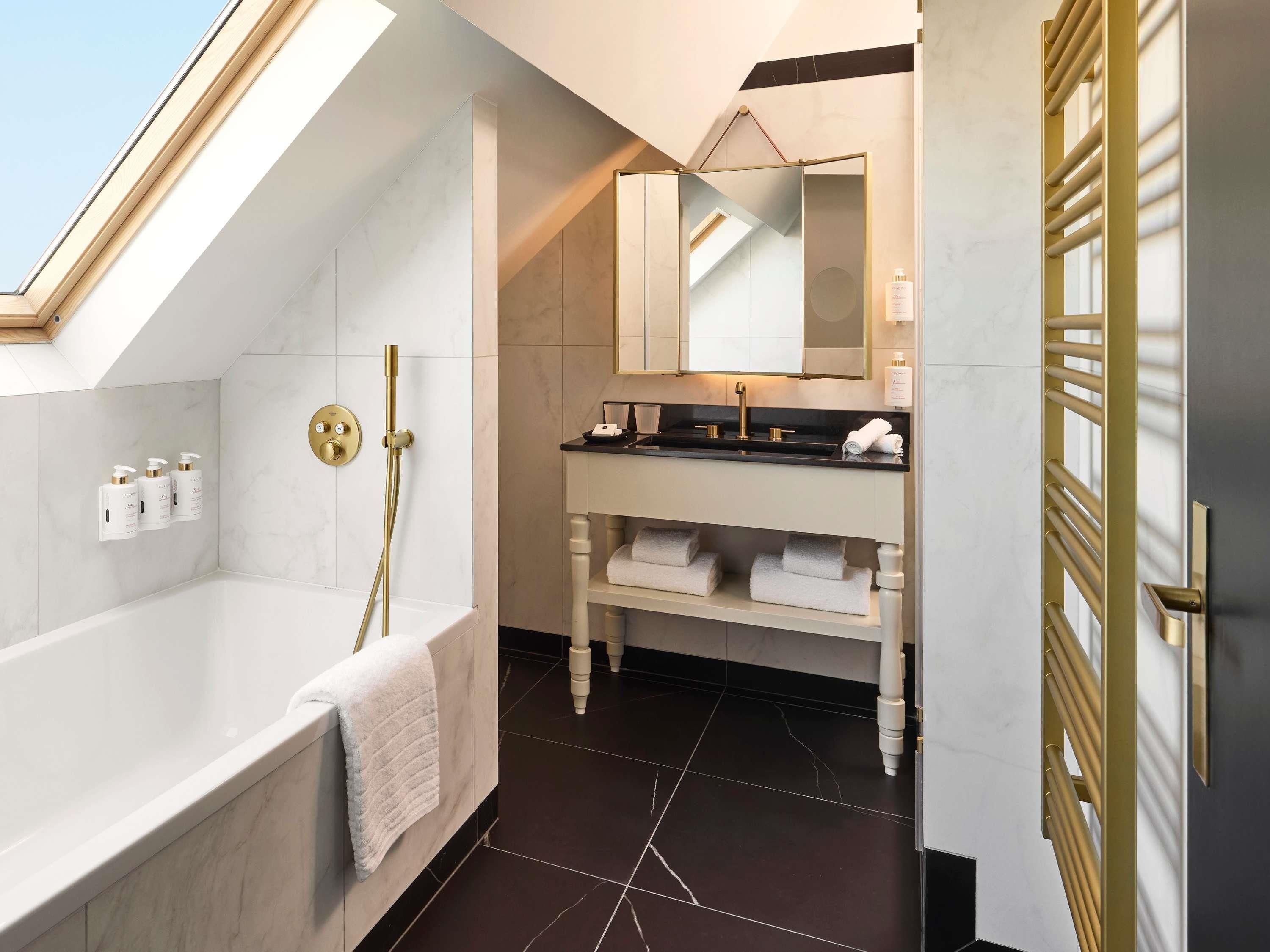 Un baño moderno con una bañera independiente, un tocador con espejo y un perchero para toallas.