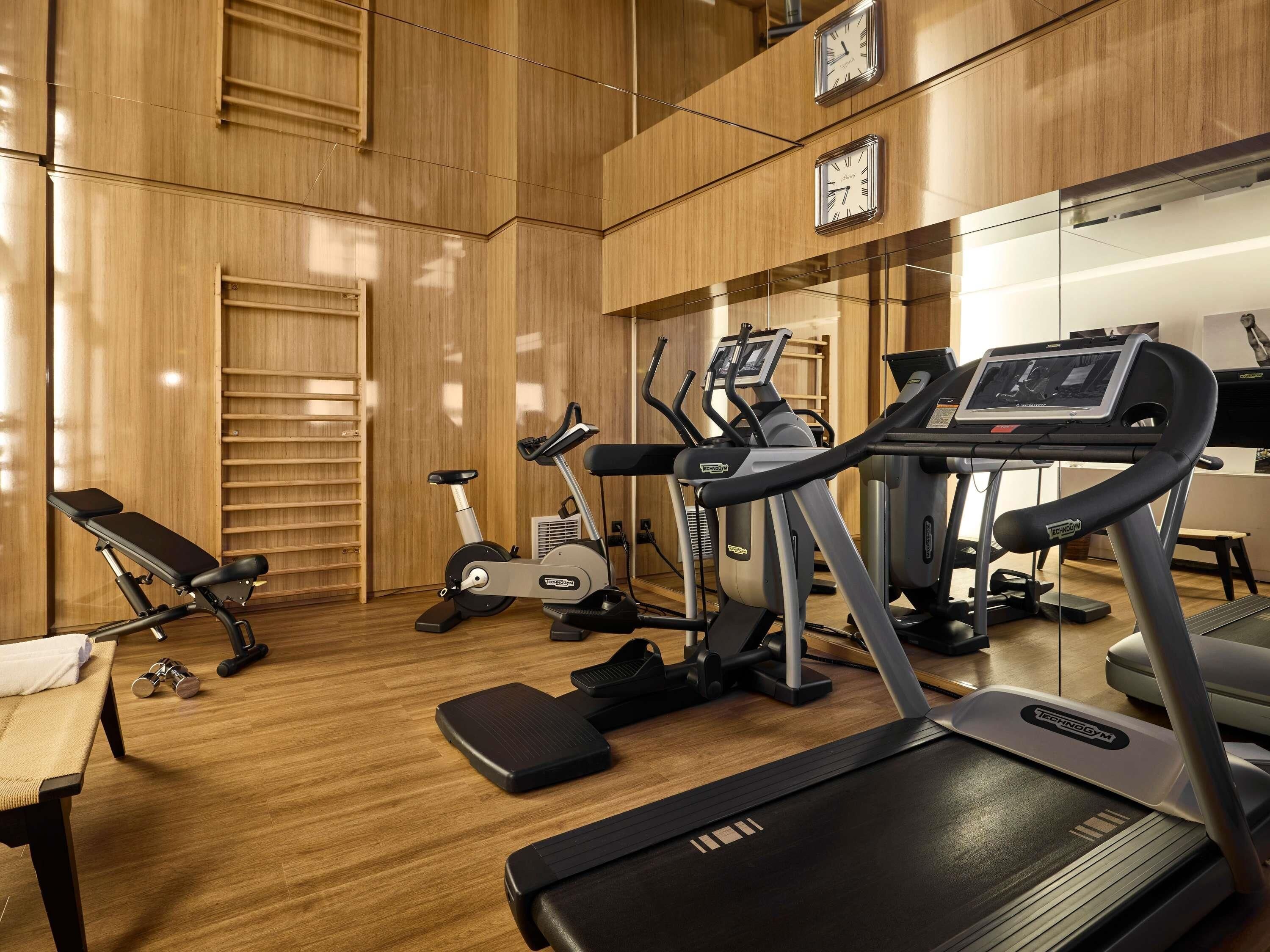 Un gimnasio con equipamiento de ejercicio, una banca y una cinta de correr.
