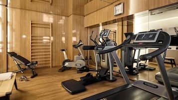 Un gimnasio con equipamiento de ejercicio, una banca y una cinta de correr.