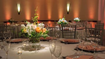 A banquet table set with fine china, glassware, and a centerpiece of flowers.