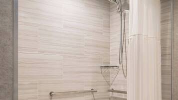 A modern bathroom with a shower, a bathtub, and a wooden bath mat.