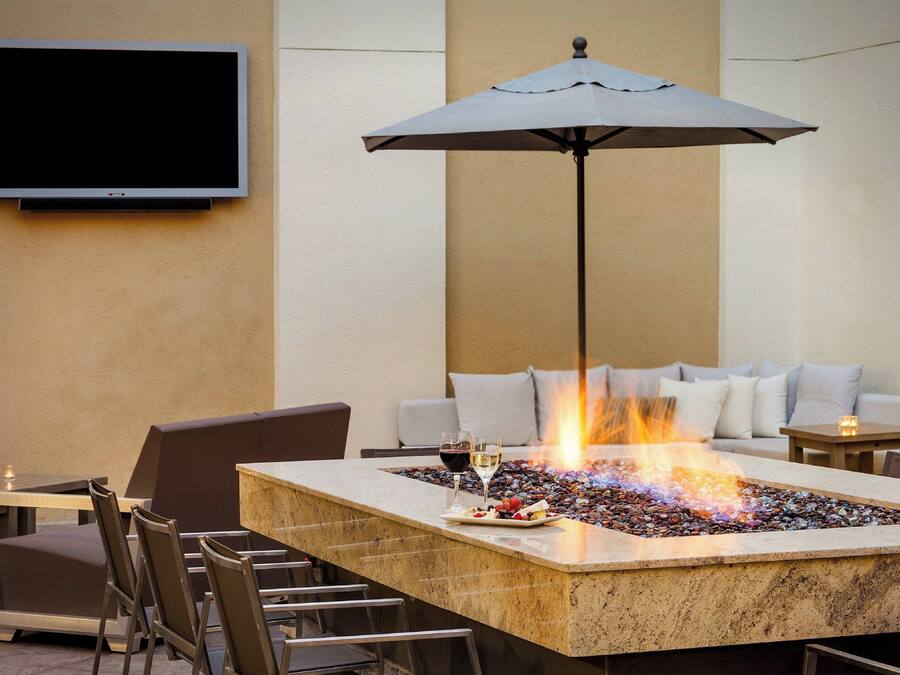 A fire feature with a table and chairs, a flat-screen TV, and a sofa in a lounge area.