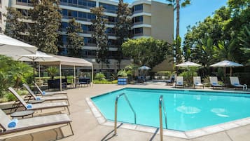 Alberca al aire libre, sombrillas en la alberca y camastros