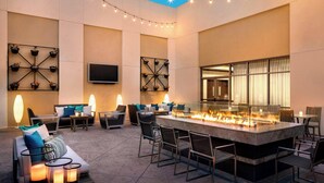 Un'area lounge esterna moderna con un elemento centrale a fuoco, comodi posti a sedere e illuminazione soffusa.