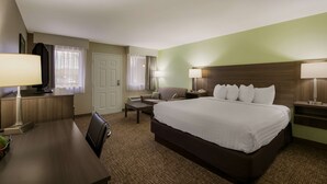 A hotel room with a large bed, a desk with a lamp, a chair, a TV, and a window with curtains. - Best Western Milton Inn (Blairsville)