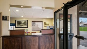 A reception desk with a framed photograph, a computer, and a sign indicating a clean environment. - Best Western Milton Inn (Blairsville)