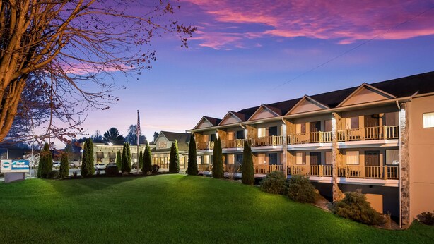 A motel with multiple-story buildings, a well-maintained lawn, and a clear view of the surrounding area. - Best Western Milton Inn (Blairsville)