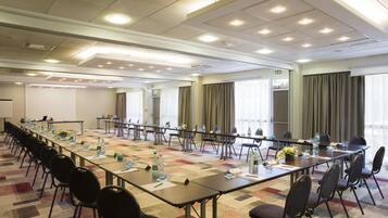 A conference room with long tables, chairs, and a carpeted floor.