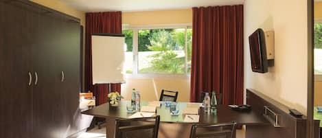 A conference room with a table, chairs, a whiteboard, and a window with curtains.