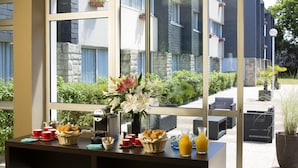 A breakfast setup with a table, baskets of bread, cups, and a vase of flowers.
